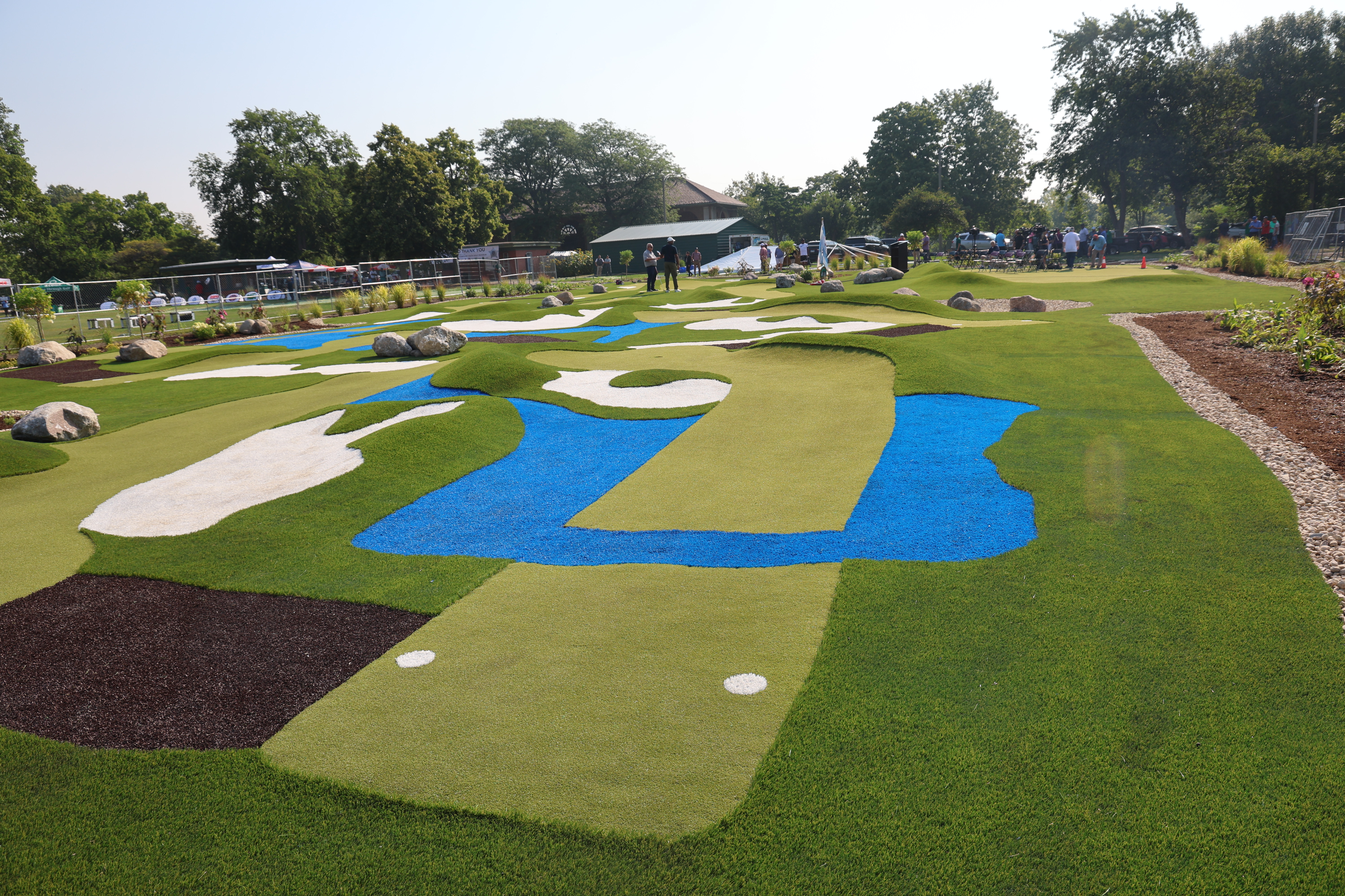 Mini golf course with green turf, blue water features, and white sand traps.